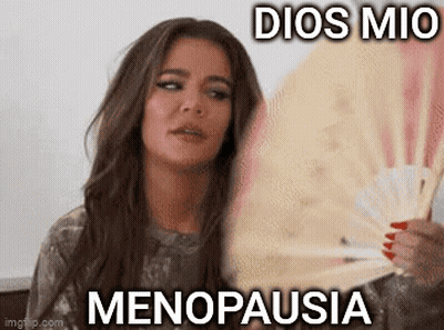 A Woman Is Holding A Fan In Her Hand With The Words `` Dios Mio Menopausia '' Written On It . GIF