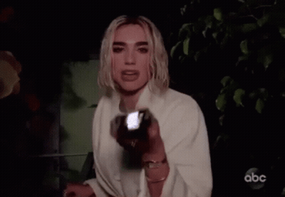 A Woman Is Holding A Flashlight In Her Hand And Looking At The Camera . GIF