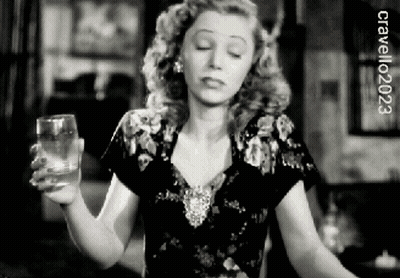A Woman Is Holding A Glass Of Water In A Black And White Photo .. GIF