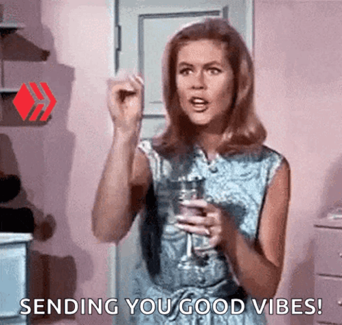 A Woman Is Holding A Glass Of Wine And Giving A Thumbs Up . GIF