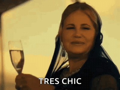 A Woman Is Holding A Glass Of Wine And Says Tres Chic GIF