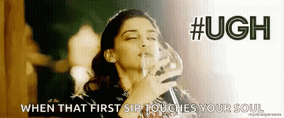 A Woman Is Holding A Glass Of Wine In Her Hand And Drinking From It . GIF