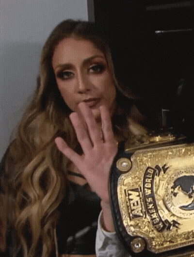 A Woman Is Holding A Gold Aew Women 'S World Championship Belt . GIF