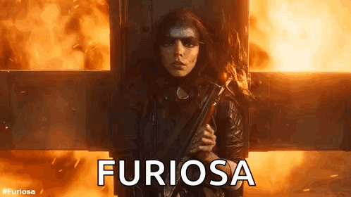 A Woman Is Holding A Gun In Front Of A Fire And The Word Furiosa Is Written On The Screen . GIF
