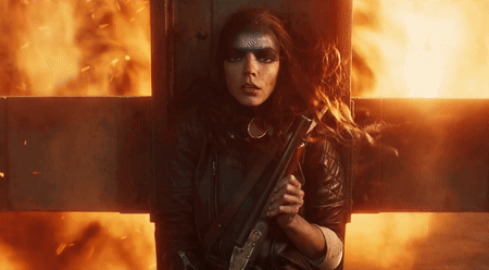 A Woman Is Holding A Gun In Front Of A Fire Cross GIF