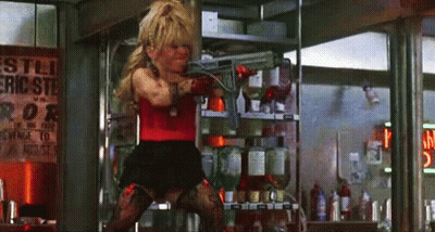 A Woman Is Holding A Gun In Front Of A Sign That Says ' Eric Ste ' On It GIF