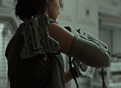 A Woman Is Holding A Gun With The Letter X On The Back GIF