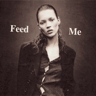 A Woman Is Holding A Hamburger And French Fries With The Words Feed Me Behind Her GIF