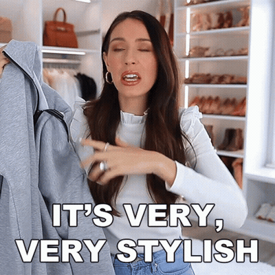 A Woman Is Holding A Jacket And Says It 'S Very Stylish GIF