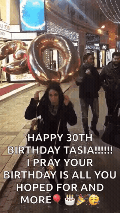 A Woman Is Holding A Large Balloon In The Shape Of A Number 30 . GIF