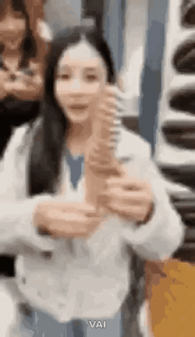 A Woman Is Holding A Large Ice Cream Cone In Her Hand . GIF