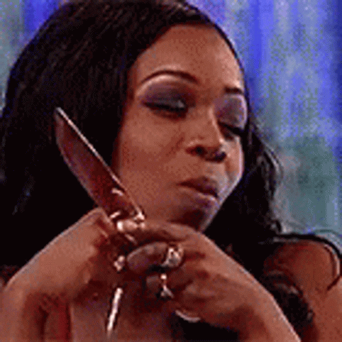 A Woman Is Holding A Large Knife In Her Hands . GIF