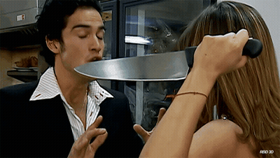 A Woman Is Holding A Large Knife Over A Man 'S Face With A Red 3D Watermark GIF