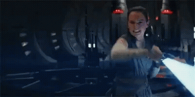 A Woman Is Holding A Light Saber In Her Hand In A Dark Room In A Star Wars Movie . GIF