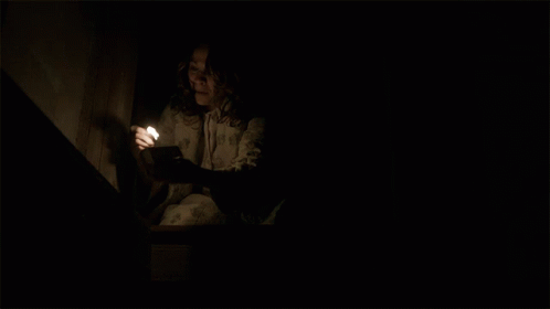 A Woman Is Holding A Lit Candle In Her Hand GIF