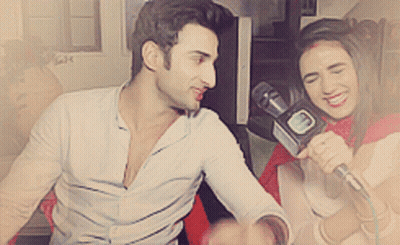 A Woman Is Holding A Microphone And Smiling While A Man Looks On GIF