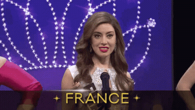 A Woman Is Holding A Microphone In Front Of A Sign That Says " France " GIF