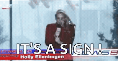 A Woman Is Holding A Microphone In Front Of A Sign That Says `` It 'S A Sign '' . GIF