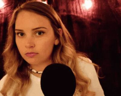 A Woman Is Holding A Microphone In Front Of Her Face And Making A Funny Face GIF