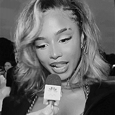 A Woman Is Holding A Microphone In Her Hand And Talking Into It . GIF