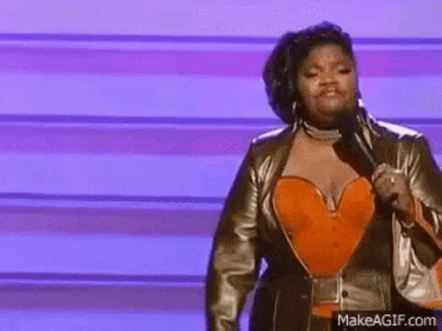 A Woman Is Holding A Microphone On A Stage . GIF