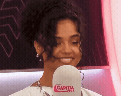 A Woman Is Holding A Microphone That Says Capital Xtra On It GIF