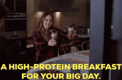A Woman Is Holding A Milkshake In A Kitchen With The Words A High Protein Breakfast For Your Big Day GIF