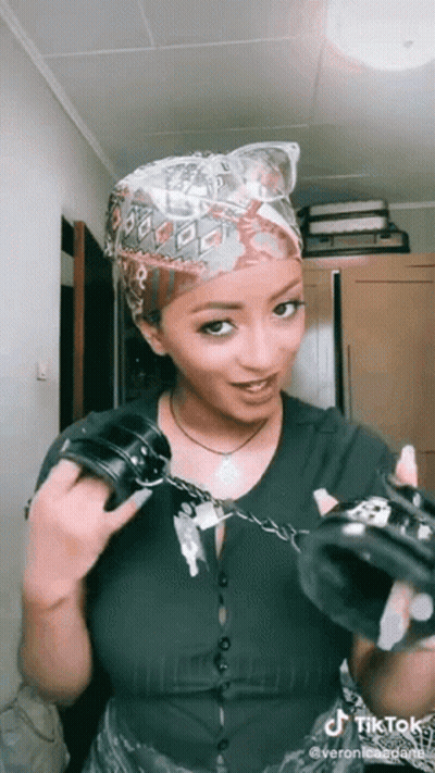 A Woman Is Holding A Pair Of Handcuffs In Her Hands . GIF
