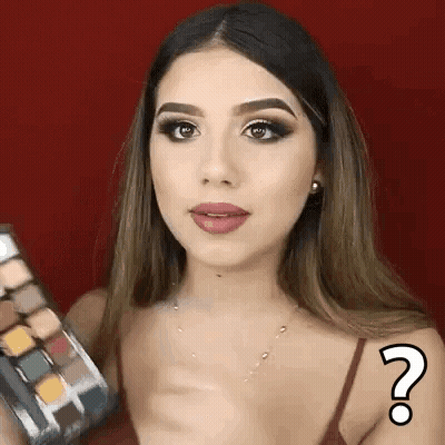 A Woman Is Holding A Palette Of Eye Shadows And Has A Question Mark On Her Arm . GIF