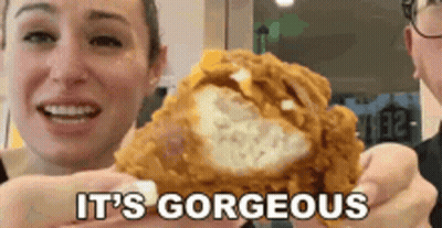 A Woman Is Holding A Piece Of Fried Chicken With The Words It 'S Gorgeous Behind Her GIF