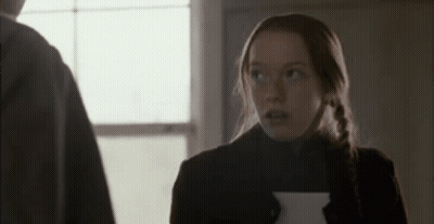 A Woman Is Holding A Piece Of Paper And Looking Up At A Man . GIF