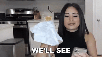 A Woman Is Holding A Piece Of Paper And Saying `` We 'Ll See '' While Standing In A Kitchen . GIF