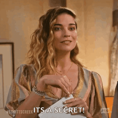 A Woman Is Holding A Piece Of Paper In Her Hand And Saying It 'S A Secret . GIF