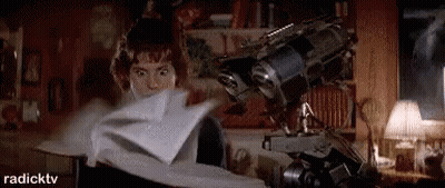 A Woman Is Holding A Piece Of Paper In Her Hand In Front Of A Robot . GIF
