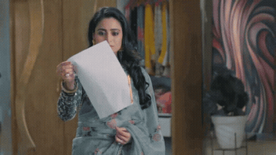A Woman Is Holding A Piece Of Paper That Is Burning . GIF