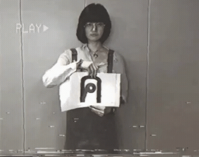 A Woman Is Holding A Piece Of Paper With The Letter A On It GIF