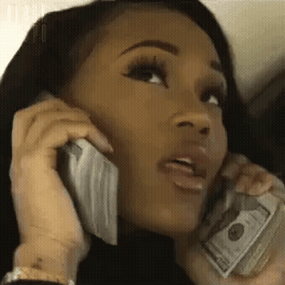 A Woman Is Holding A Pile Of Money And Talking On A Cell Phone . GIF