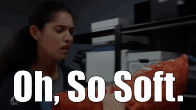 A Woman Is Holding A Pillow With The Words Oh So Soft Written Above Her GIF