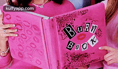 A Woman Is Holding A Pink Book Called The Burn Book GIF