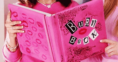 A Woman Is Holding A Pink Burn Book With Kisses On It GIF