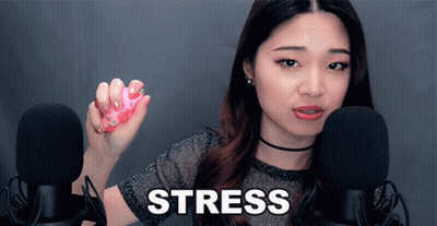 A Woman Is Holding A Pink Object In Front Of Two Microphones And The Word Stress Is On The Screen Behind Her GIF