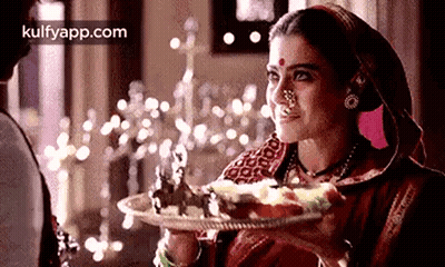 A Woman Is Holding A Plate Of Food In Her Hand And Smiling At A Man . GIF