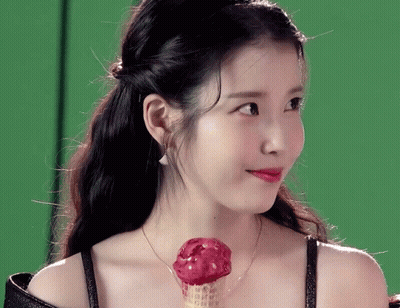A Woman Is Holding A Red Ice Cream Cone In Her Hand GIF