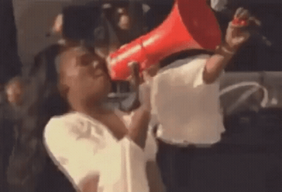 A Woman Is Holding A Red Megaphone In Her Mouth And Shouting Into It . GIF