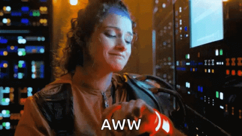 A Woman Is Holding A Red Object With The Word Aww Written On It . GIF