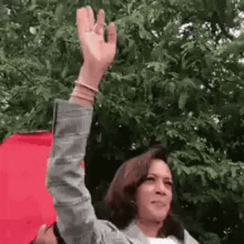 A Woman Is Holding A Red Umbrella And Waving Her Hand In The Air . GIF
