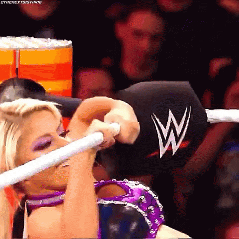 A Woman Is Holding A Rope In A Wrestling Ring While Wearing A Purple And Silver Outfit . GIF