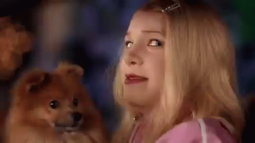 A Woman Is Holding A Small Dog In Her Arms And Looking At It . GIF