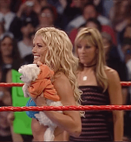 A Woman Is Holding A Small White Dog In Her Arms GIF