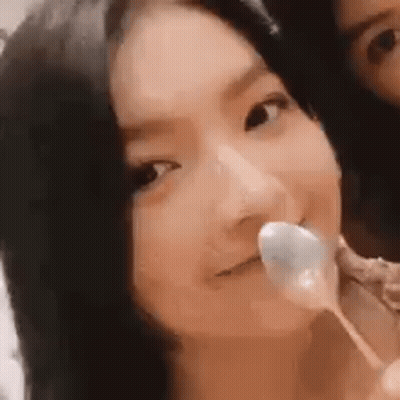 A Woman Is Holding A Spoon In Her Mouth While Another Woman Looks On . GIF